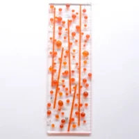 A bubbly orange suncatcher with orange and dichroic glass beads and stringers fused onto an oblong shaped piece of clear glass.