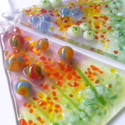 Close up of two handmade glass suncatchers with tactile and quirky design.