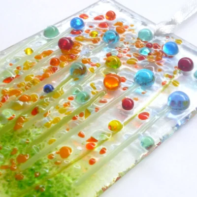 Close up and side view of multicoloured glass flower suncatcher, showing tactile and quirky design.