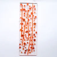 A bubbly orange fused glass suncatcher with orange and dichroic glass beads and stringers fused onto an oblong shaped piece of clear glass. Hanging from a clear cord.