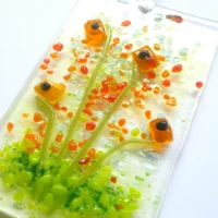 Close up of handmade orange glass flower suncatcher showing detail and tactile design.