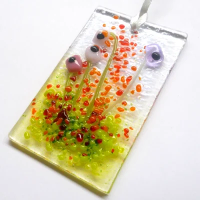 Pink and lilac glass flower suncatcher laying at an angle showing tactile design.
