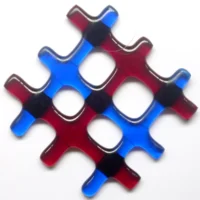 Small red and blue lattice fused glass suncatcher hanging from a clear wire. Glass strips of three red and three blue, have fused into a lattice design and has four holes in the middle.