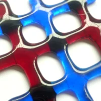 Close up of red and blue lattice fused glass suncatcher showing depth and colour.