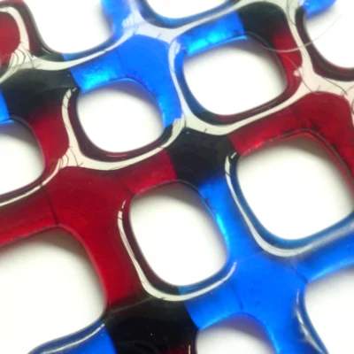 Close up of red and blue lattice fused glass suncatcher showing depth and colour.
