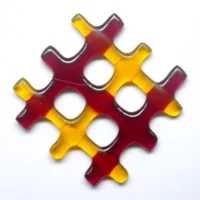 Small red and yellow lattice fused glass suncatcher. Three red and three yellow strips of glass have been fused in a lattice design. Hangs from a clear cord.