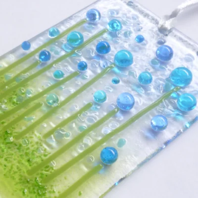 Close up of blue and turquoise glass flower suncatcher, showing tactile and colourful design.