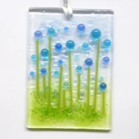Small rectangle blue and turquoise glass flower suncatcher with quirky bead flowers with stringer stems. Hanging from a white ribbon.