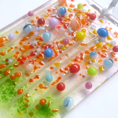 Close up of small handmade glass flower suncatcher, showing tactile and colourful quirky design.
