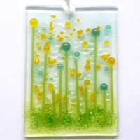 Quirky handmade yellow glass flower suncatcher with yellow and green tactile beads and strings. Hole drilled at the top with white ribbon threaded through.
