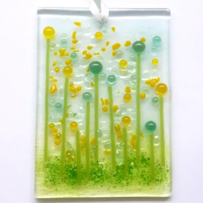 Quirky handmade yellow glass flower suncatcher with yellow and green tactile beads and strings. Hole drilled at the top with white ribbon threaded through.